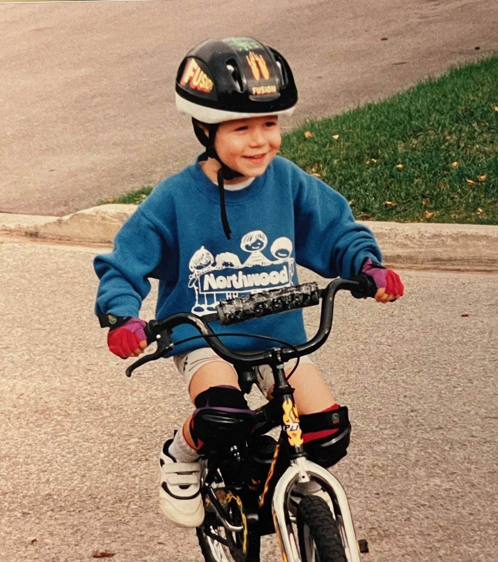 Michael as a kid, smiling on his first bike